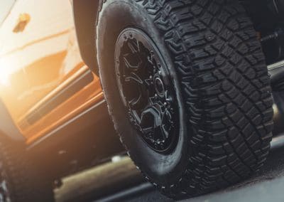 Modern Performance Off Road Wheels and Tires Installed to All Terrain Sport Utility Vehicle with Heavy Duty Suspension. Close Up Photo.