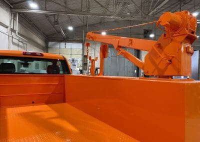 Bright orange custom paint job on a specialized small crane service pickup truck to match the fleet color